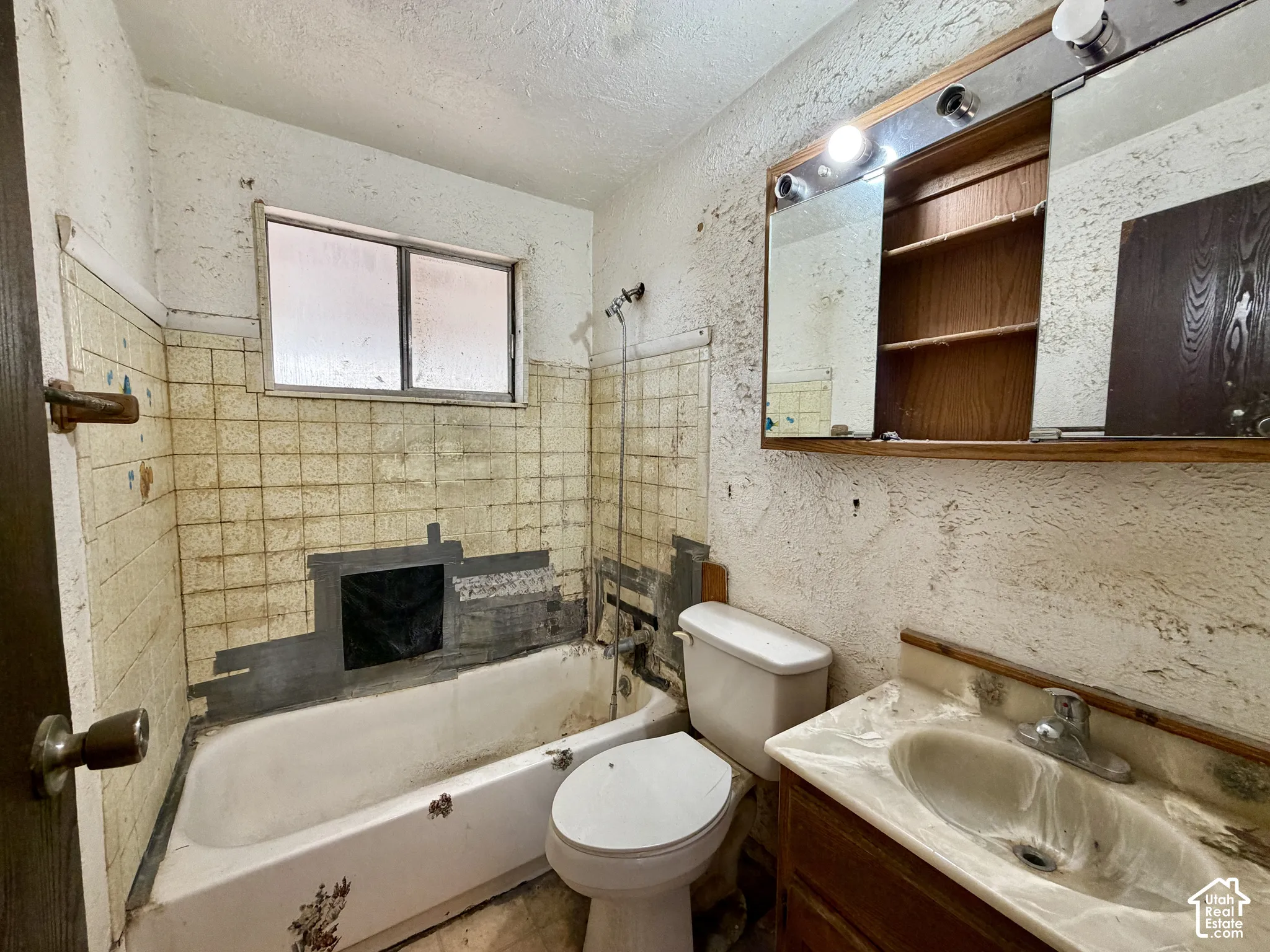Bathroom featuring a bathtub, tile wall surround, built-in medicine cabinet, and a single-basin vanity