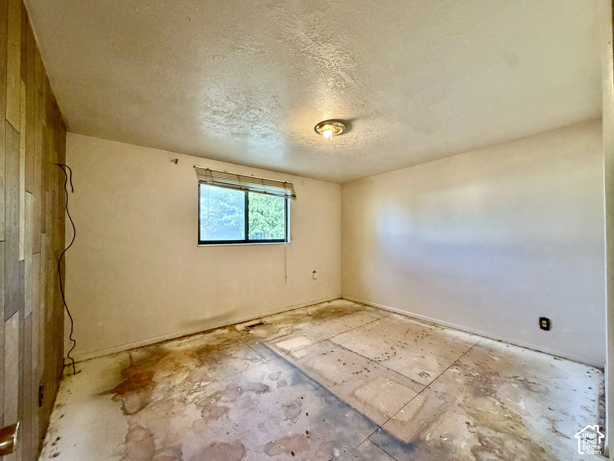 Interior room featuring a textured accent wall, single-pane window, and flush-mount ceiling lighting
