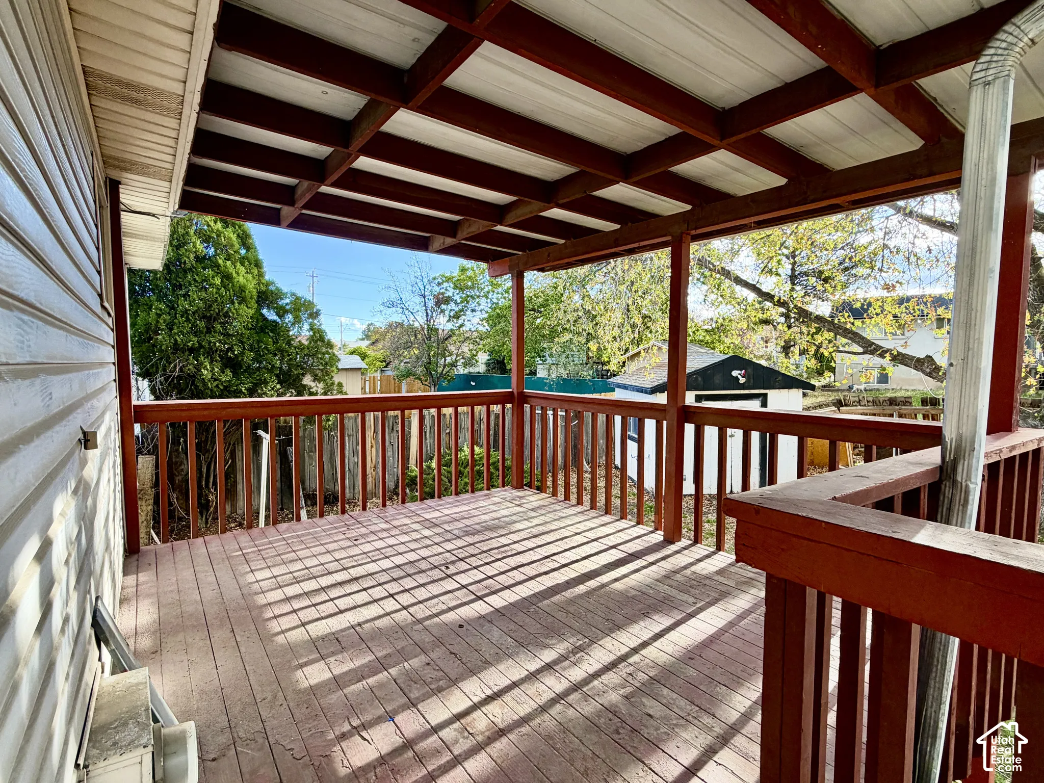 Covered wood-plank deck featuring a wooden railing system and an open-rafter ceiling structure