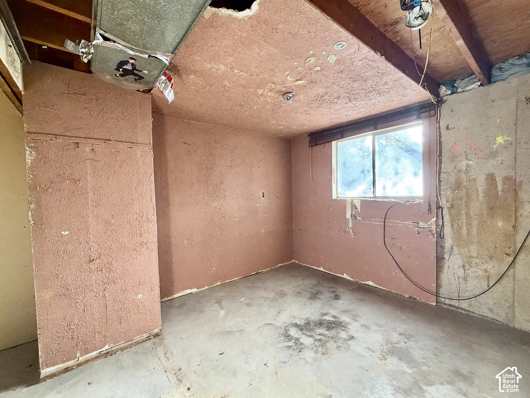 Interior space featuring exposed wood ceiling joists, concrete flooring, single-pane window, and textured walls