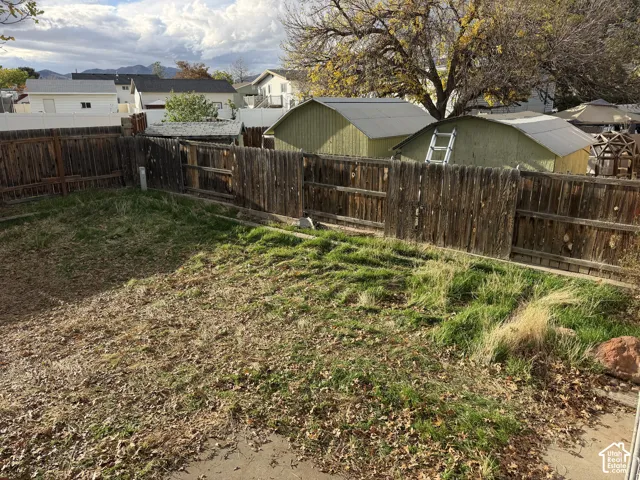 Backyard area featuring a wood-plank perimeter fence and two detached storage structures