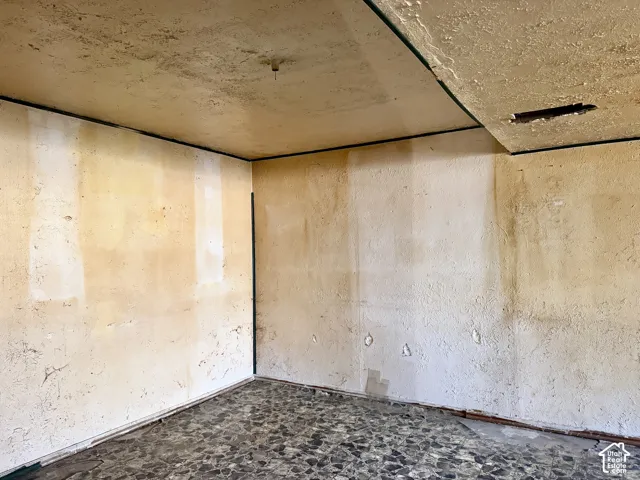 Interior room featuring textured plaster wall finishes and dark aggregate stone flooring