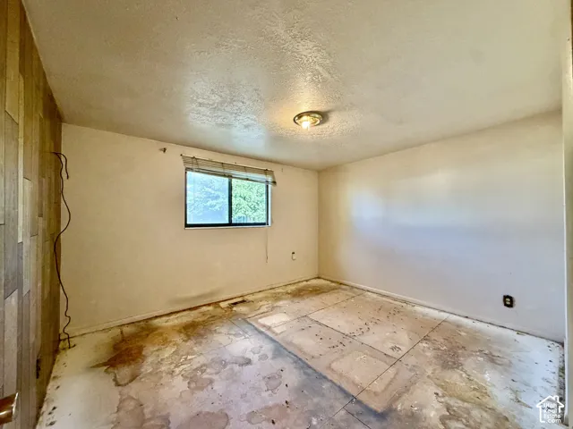 Interior room featuring a textured accent wall, single-pane window, and flush-mount ceiling lighting