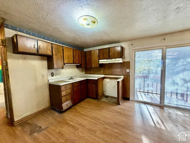 Kitchen featuring wood cabinetry, white laminate countertops, integrated sink, wood-finish flooring, and sliding glass doors
