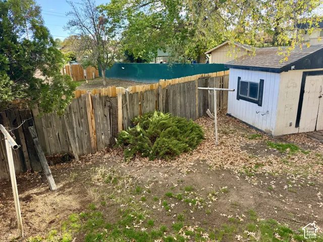 Outdoor area featuring a wood-slat privacy fence, a detached storage shed, and mature greenery