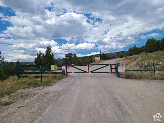 Gated entry featuring a metal swing-arm barrier and wooden fencing