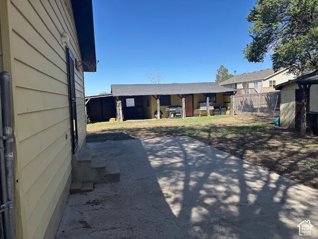 Backyard featuring a concrete patio, detached structure, and perimeter fencing