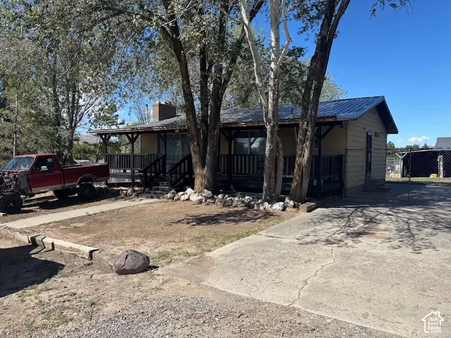 Single-story exterior featuring metal roofing, horizontal siding, and a covered front porch with wooden railings