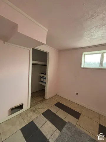 Room featuring large-format ceramic tile flooring, a recessed storage nook with built-in shelving, and a horizontal frosted-glass window