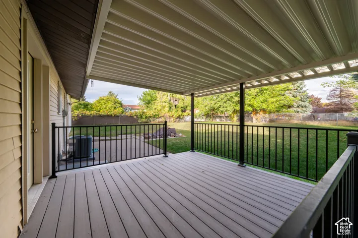 Covered deck featuring composite decking, black metal railings, and a corrugated metal patio cover
