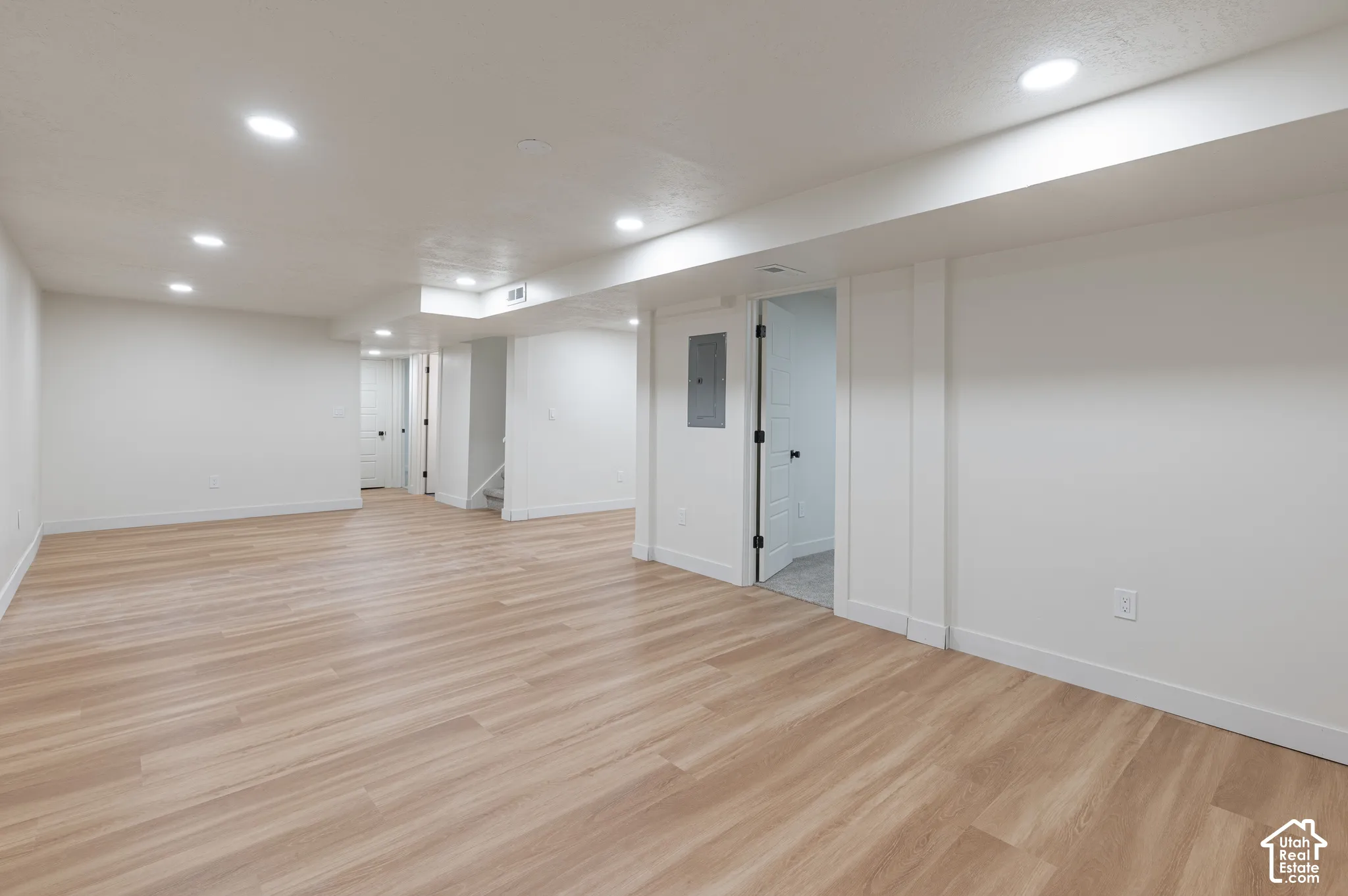 Open floor plan featuring wood-finish flooring, recessed lighting, and crisp white wall finishes