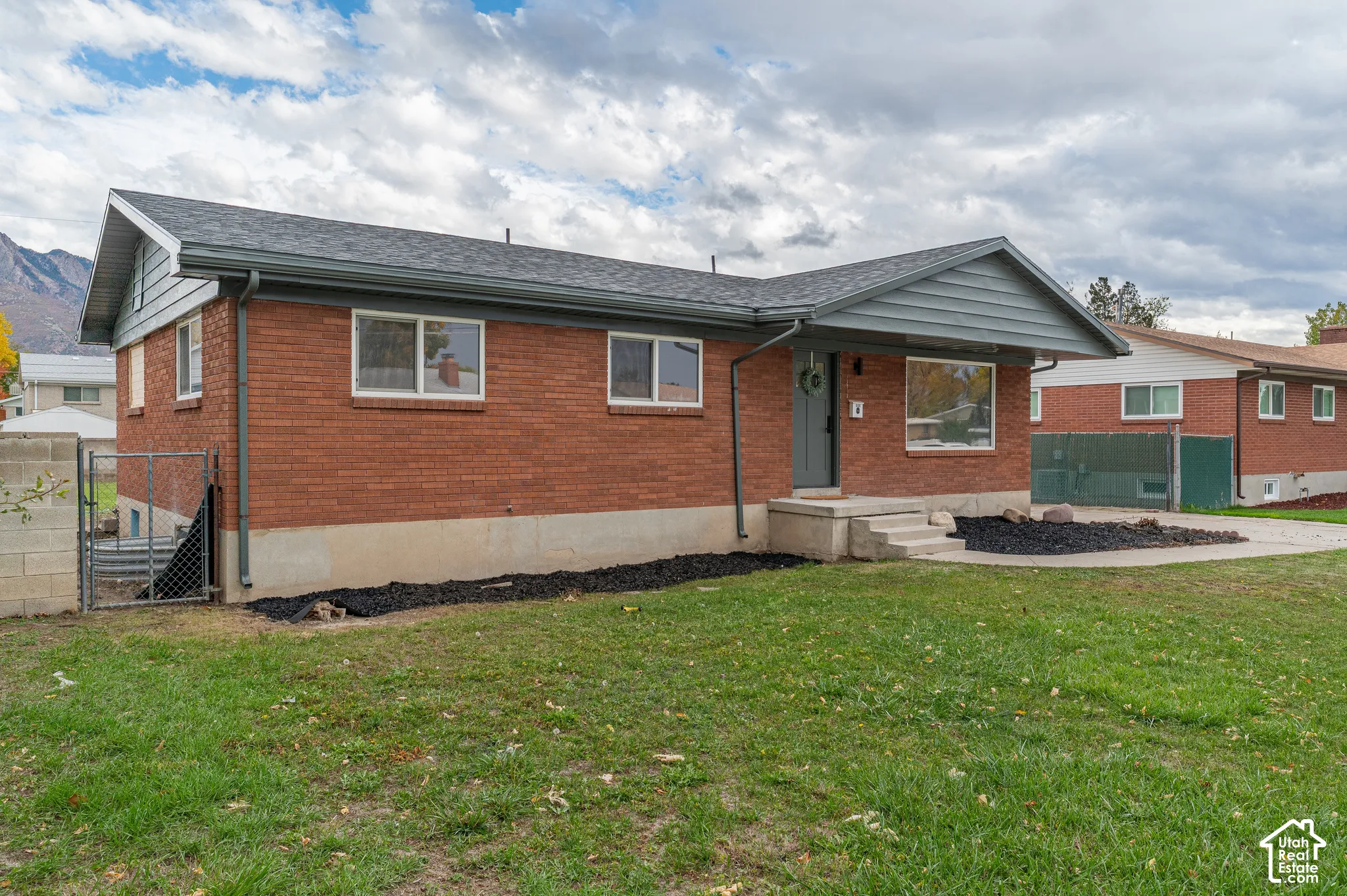 Single-story brick exterior featuring a multi-gabled roofline, horizontal siding accents, concrete foundation, and a concrete driveway