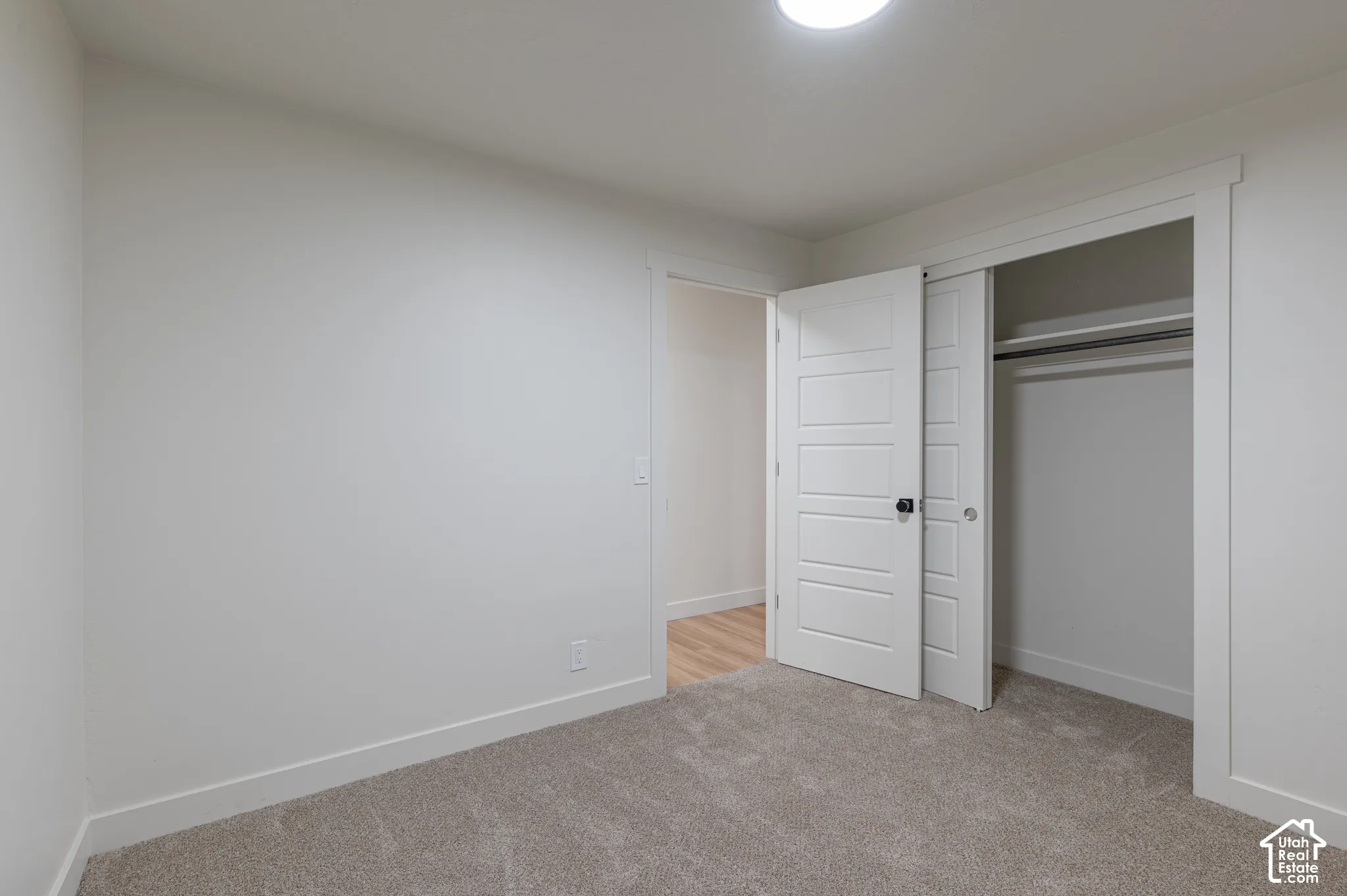 Neutral-toned carpeting, five-panel interior doors with matte black hardware, and built-in closet shelving