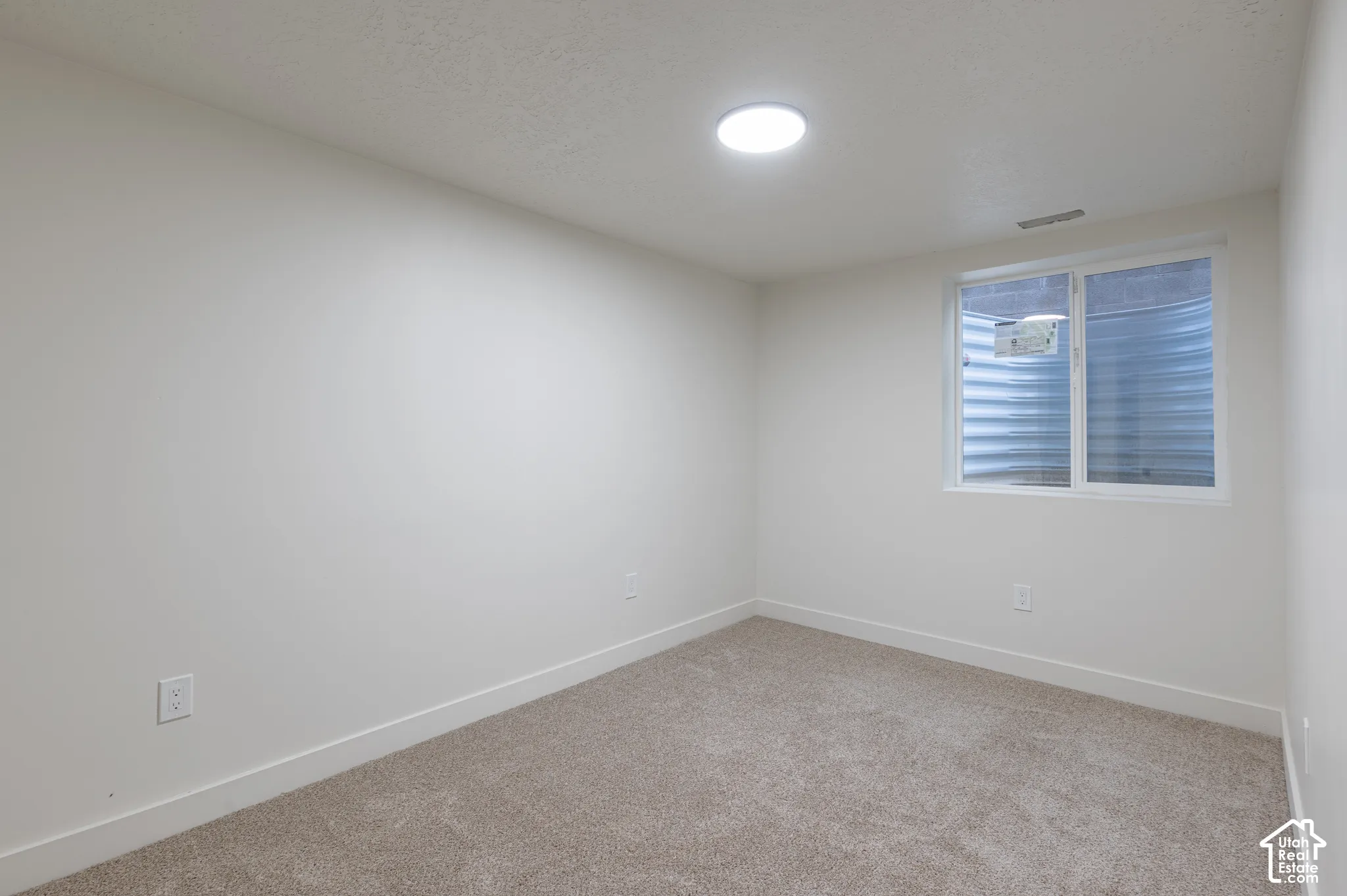 Neutral interior featuring wall-to-wall carpeting, smooth-finish walls, and a recessed window well with a sliding window