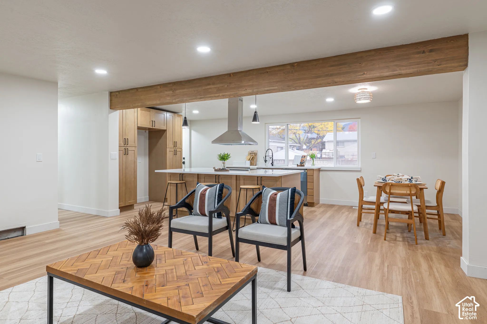 Kitchen featuring light wood cabinetry, a central island with a countertop, stainless steel range hood, recessed lighting, and wood-finish flooring with an exposed structural beam
