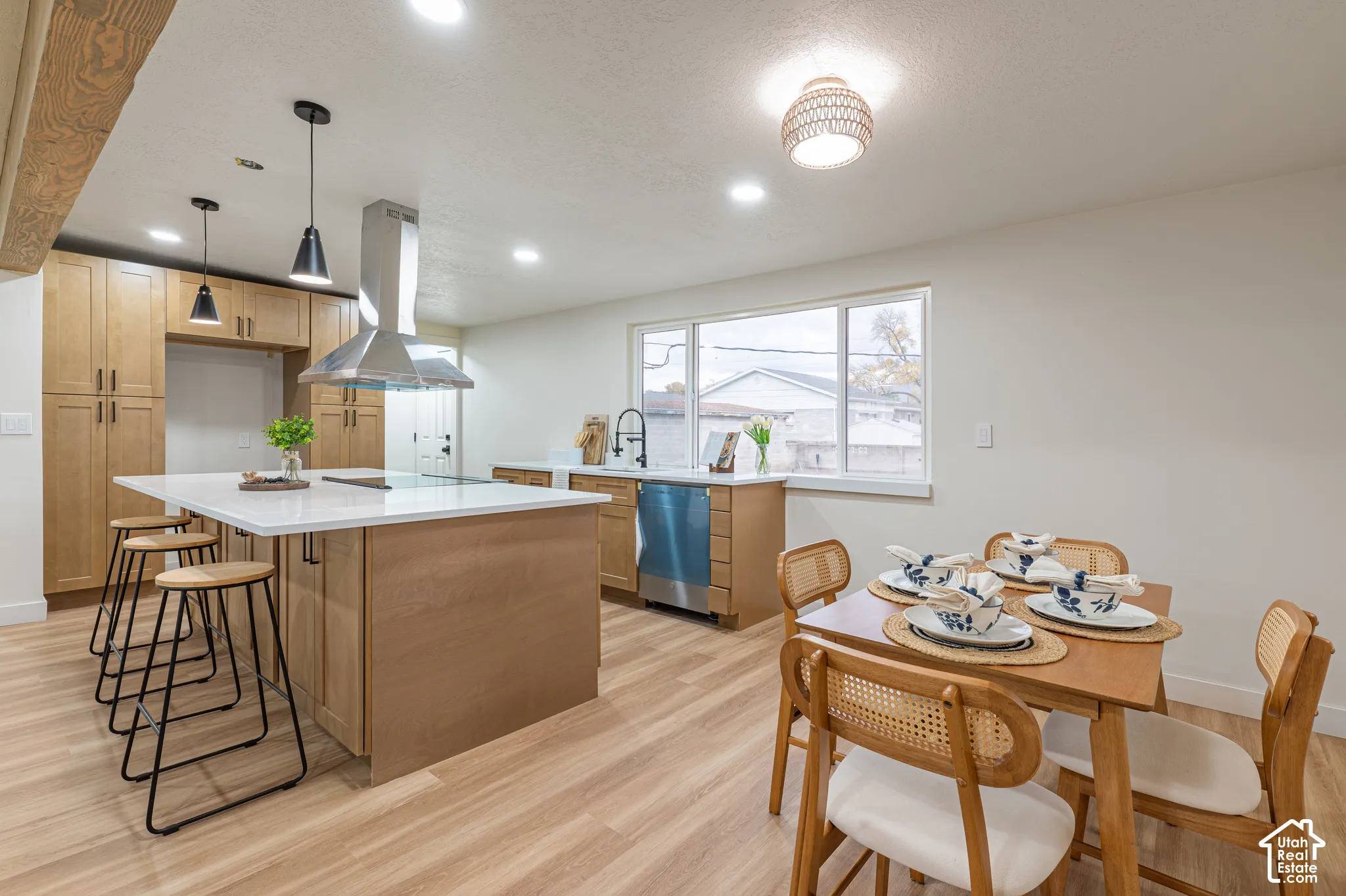 Kitchen featuring wood-finish cabinetry, a central island with a stone-surface countertop, stainless steel chimney-style range hood, wood-finish flooring, and recessed lighting