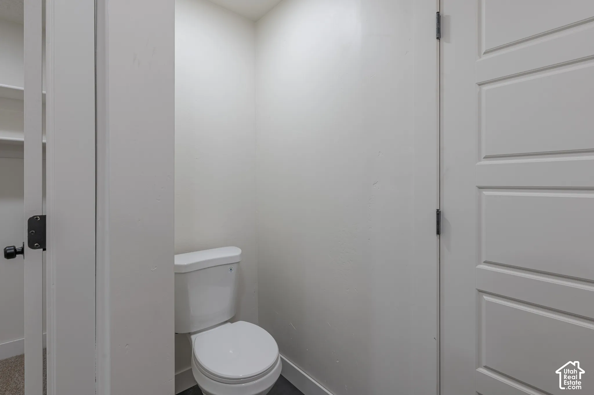 Standard-height porcelain toilet featuring a dual-flush actuator and a four-panel interior door