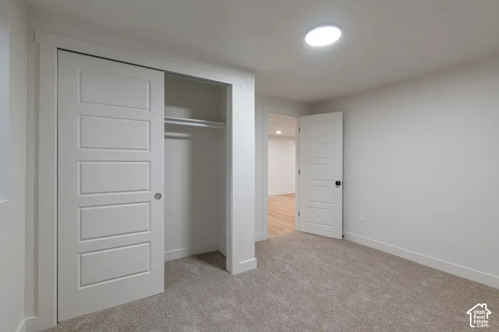 Room featuring neutral-toned carpeting, five-panel interior doors, a sliding closet door, and a flush-mount ceiling light fixture