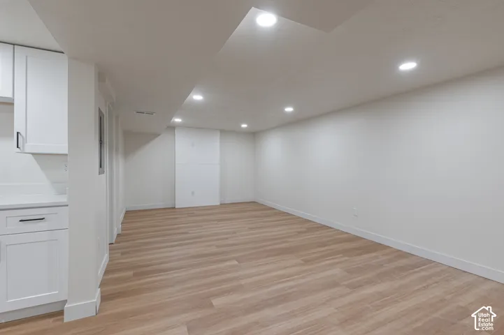 Open-concept room featuring wood-finish flooring, recessed lighting, white shaker-style cabinetry, and white shiplap accent wall detailing
