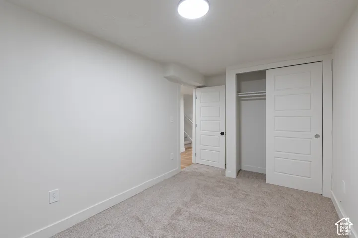 Neutral-toned room featuring fitted carpeting, a ceiling-mounted light fixture, a closet with sliding panel doors, and paneled interior doors