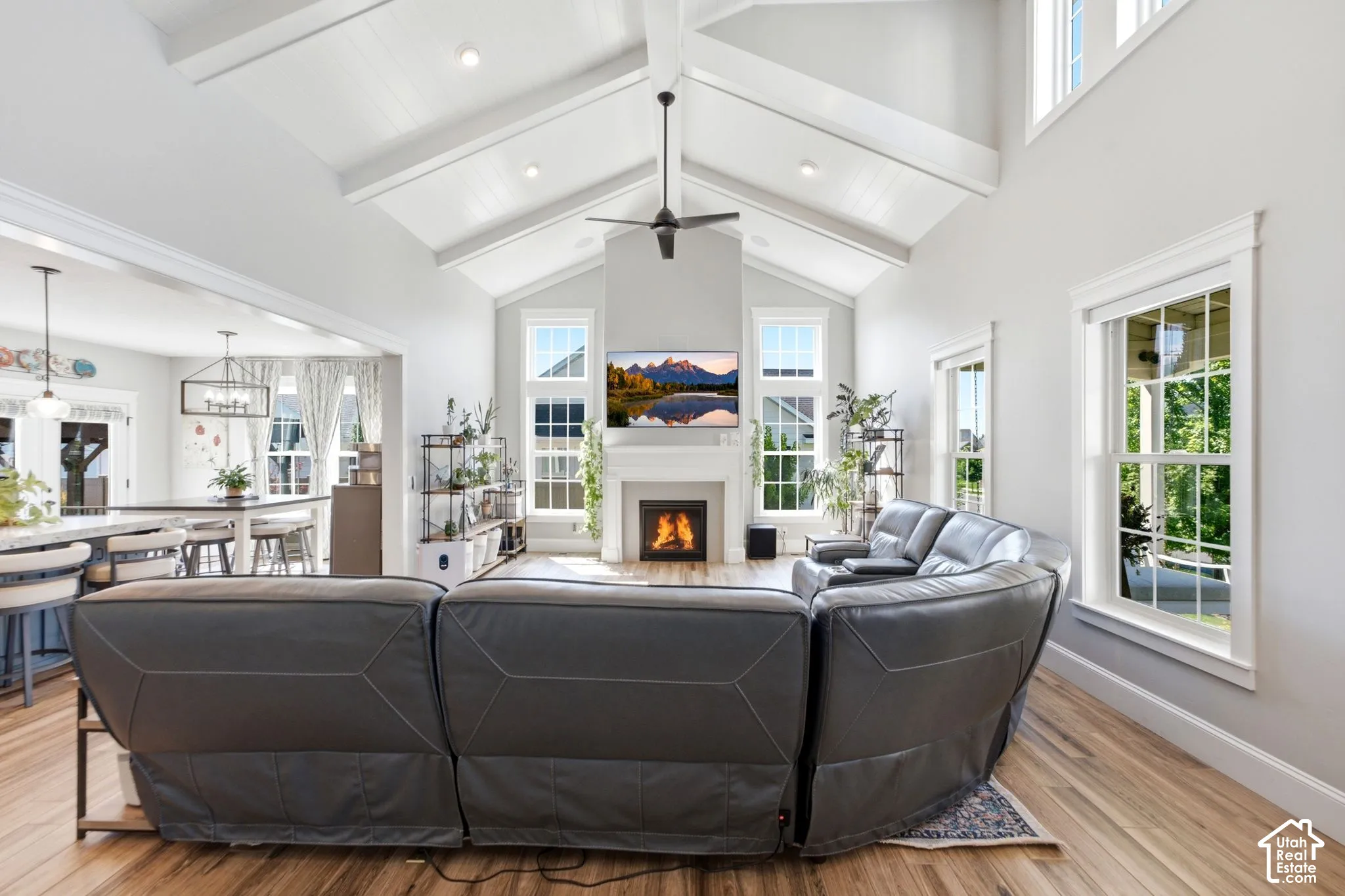 Vaulted ceiling with exposed beams, wood-finish flooring, large window that have electric blinds and gas fireplace