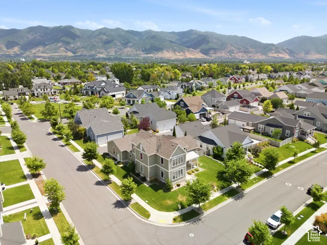 Aerial view featuring multi-story residential architecture, corner lot placement, and prominent mountain backdrop