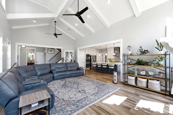 Vaulted ceilings with exposed beams, wood-finish flooring, and dual matte black ceiling fans