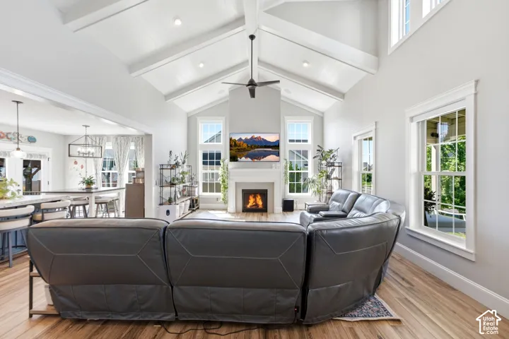 Vaulted ceiling with exposed beams, wood-finish flooring, large window that have electric blinds and gas fireplace