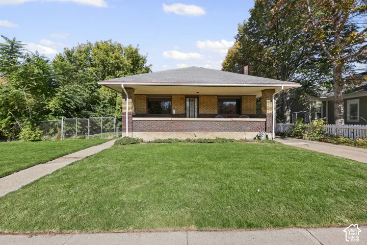 Single-story brick exterior featuring a covered front porch, low-slope hip roof, and concrete driveway