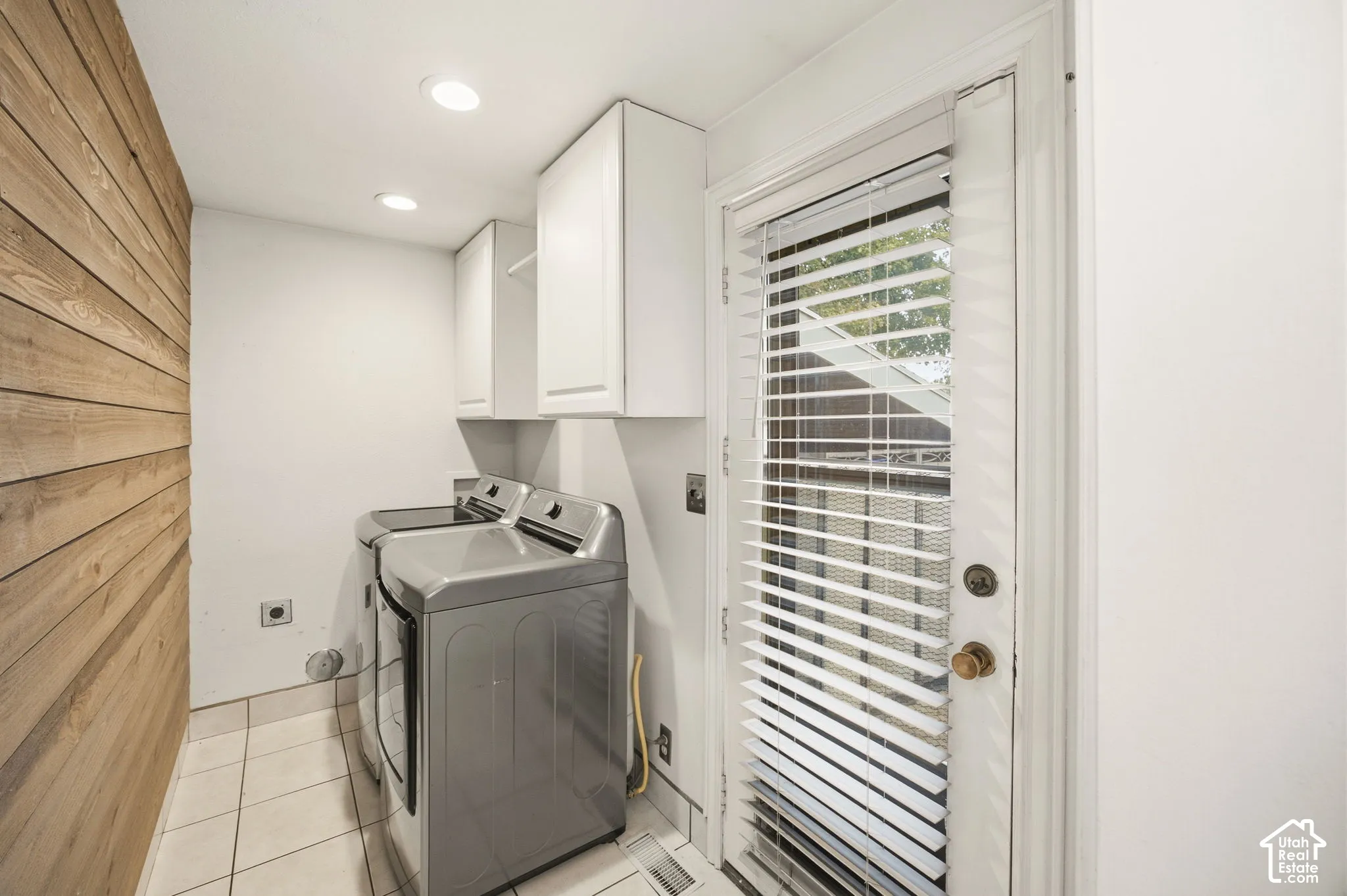 Horizontal wood-plank accent wall, white upper cabinetry, tiled flooring, and recessed ceiling lighting