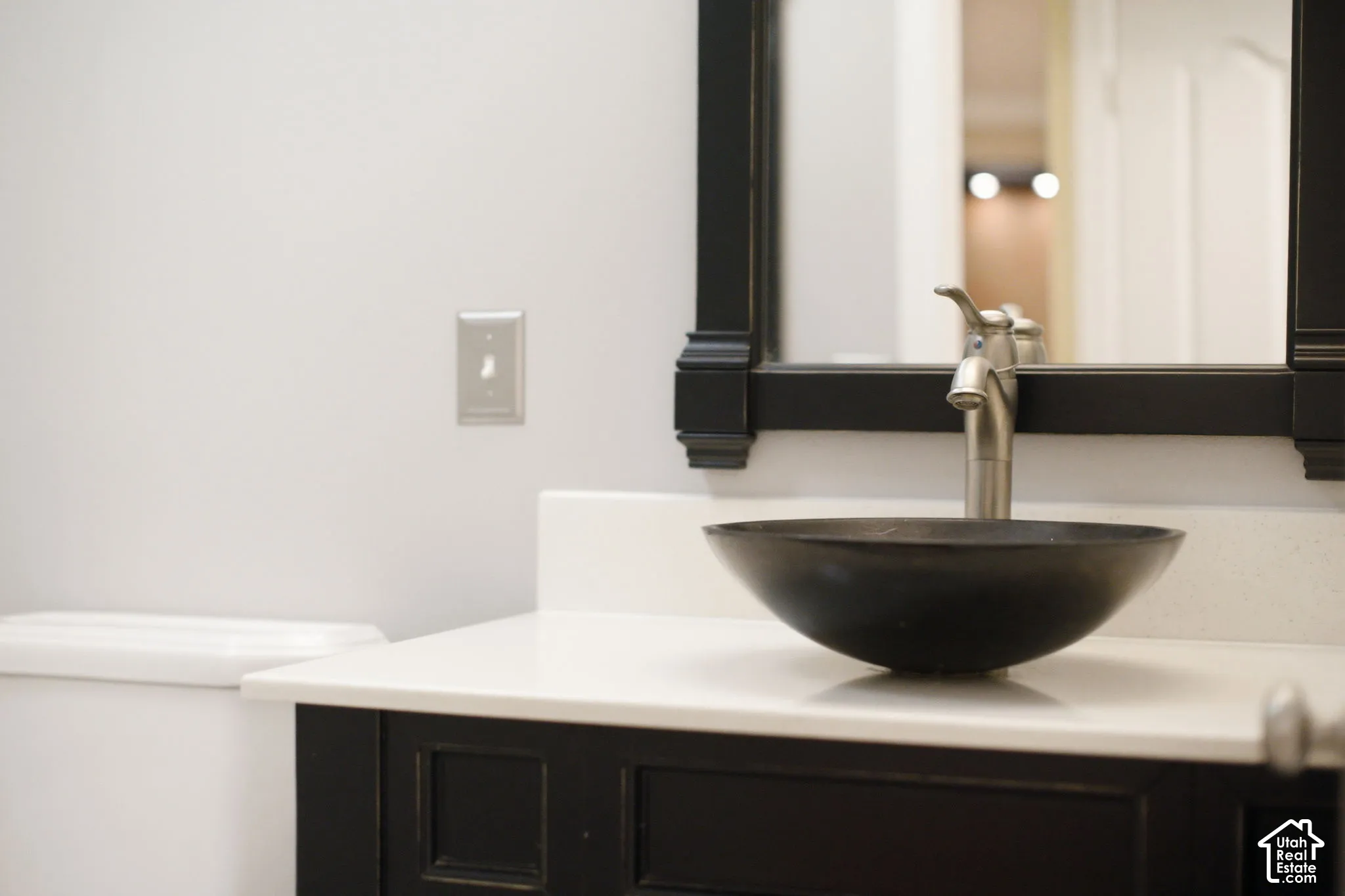 Vanity featuring a matte black base cabinet, solid surface countertop, black vessel sink, high-arc faucet, and matching black framed mirror