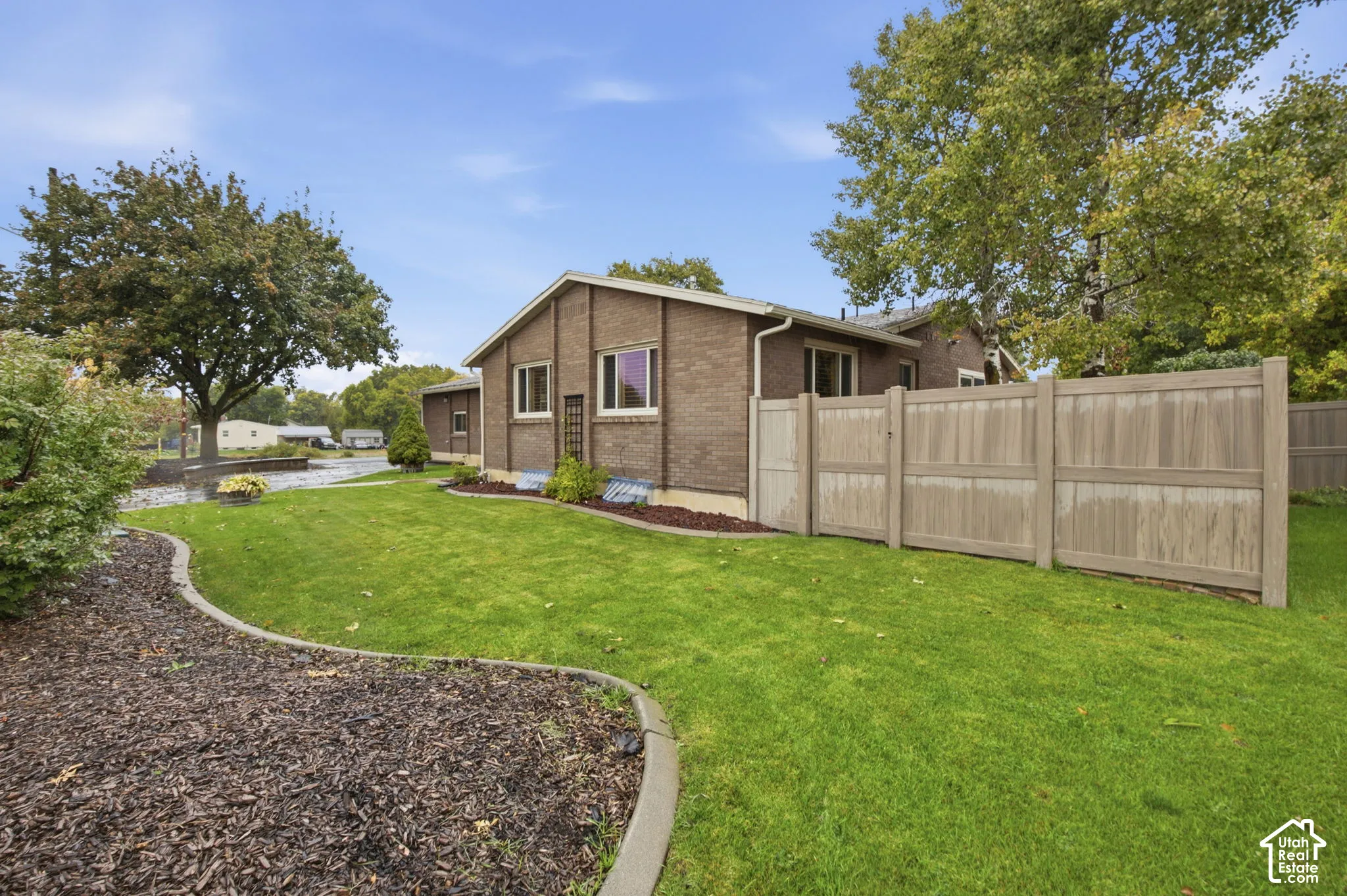 Brick exterior, privacy fencing, manicured lawn, and defined landscape edging