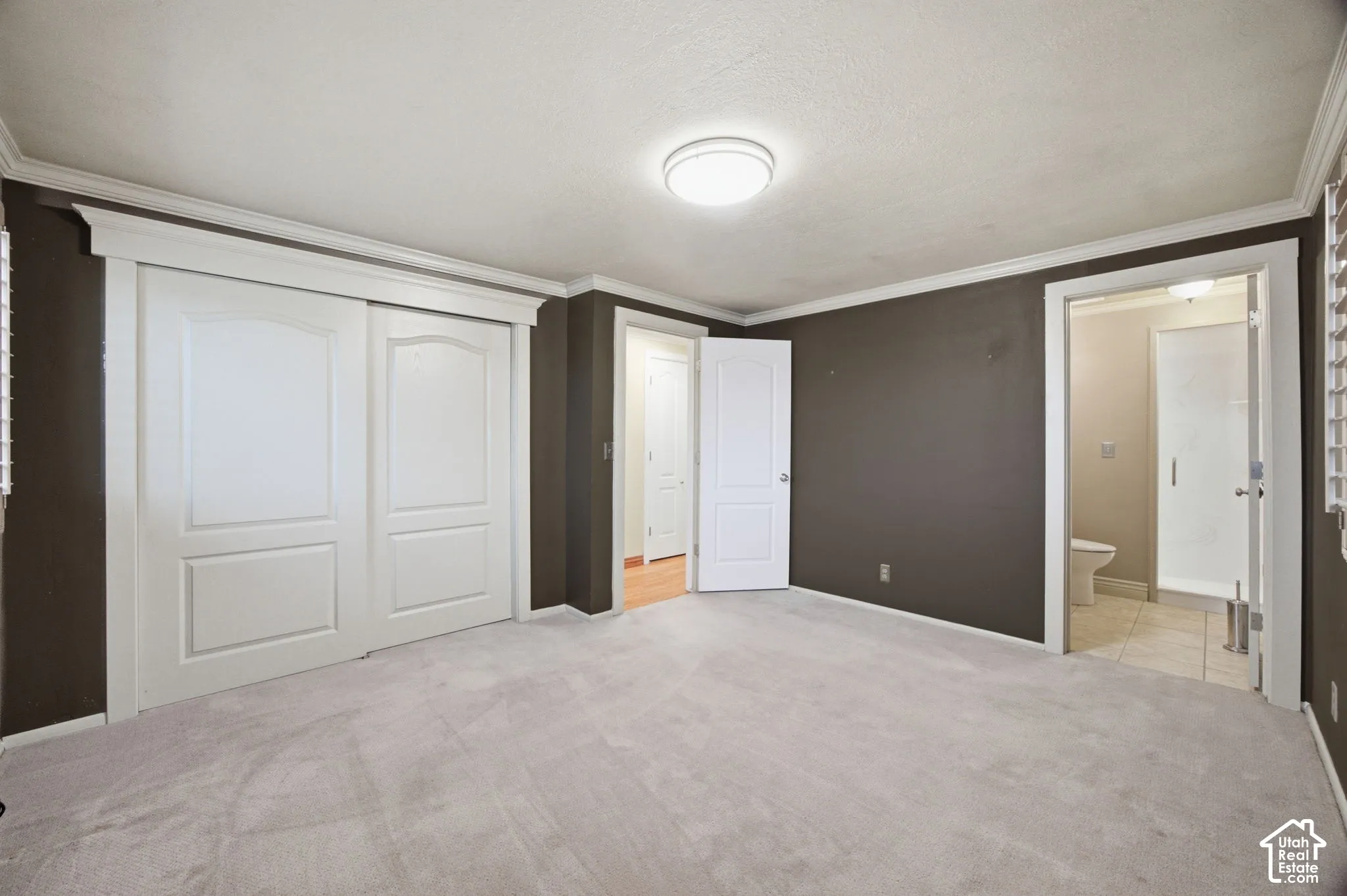 Primary Bedroom featuring crown molding, neutral carpeting, multi-panel closet doors, and recessed lighting