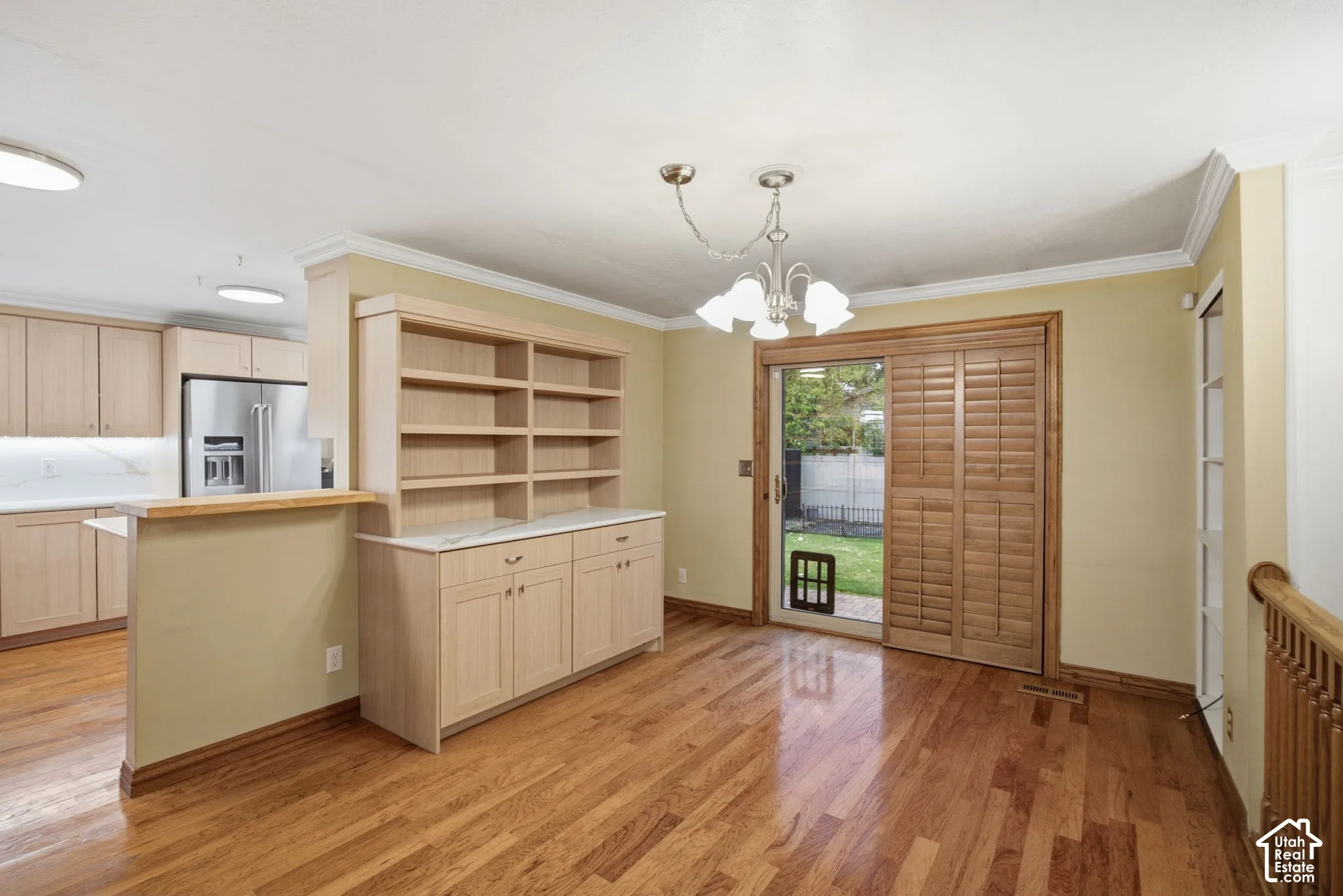 Dining area featuring wood-finish flooring, built-in cabinetry with stone-finish countertops, sliding glass door with wood-finish shutters, and multi-light hanging fixture