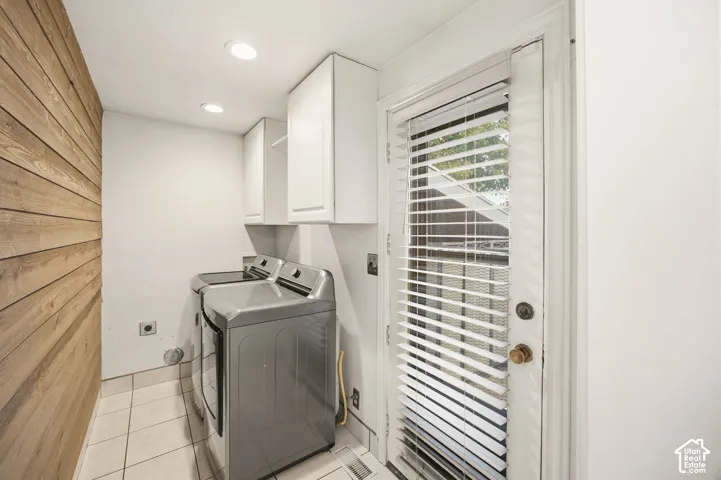 Horizontal wood-plank accent wall, white upper cabinetry, tiled flooring, and recessed ceiling lighting