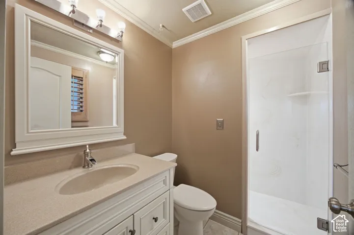 Primary Bathroom featuring a white vanity with a composite countertop and integrated sink, a framed wall mirror with multi-light fixture, and a glass-enclosed shower with tiled surround
