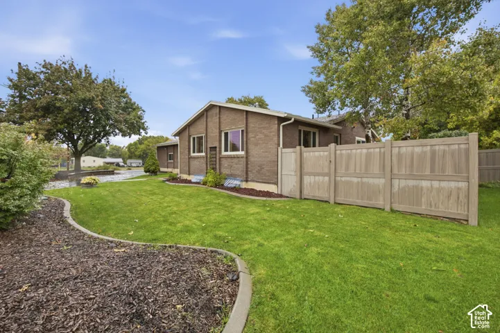 Brick exterior, privacy fencing, manicured lawn, and defined landscape edging