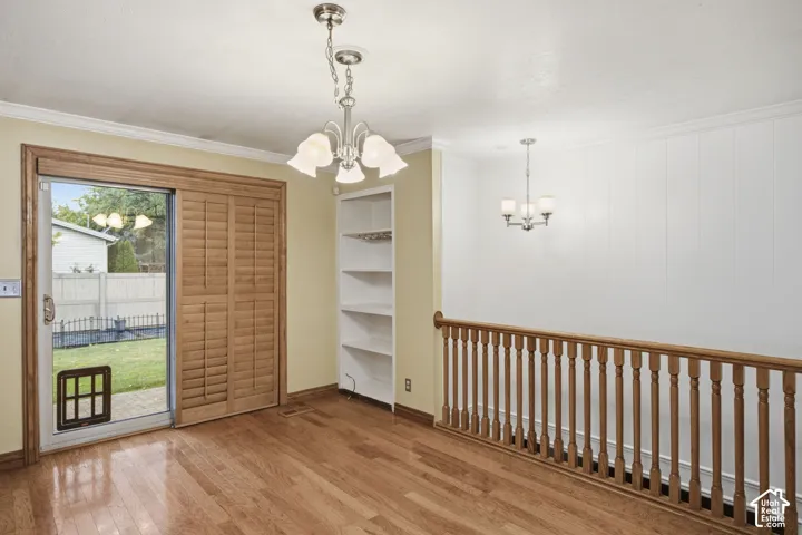 Wood-finish flooring, built-in shelving, glass sliding door with wood casing, and wooden staircase railing with spindle balusters