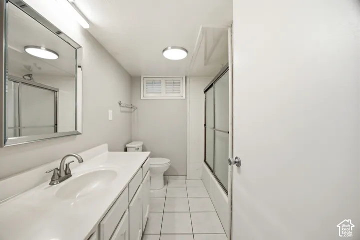 Bathroom featuring a white vanity with an integrated sink, polished chrome faucet, rectangular wall-mounted mirror, and tile flooring