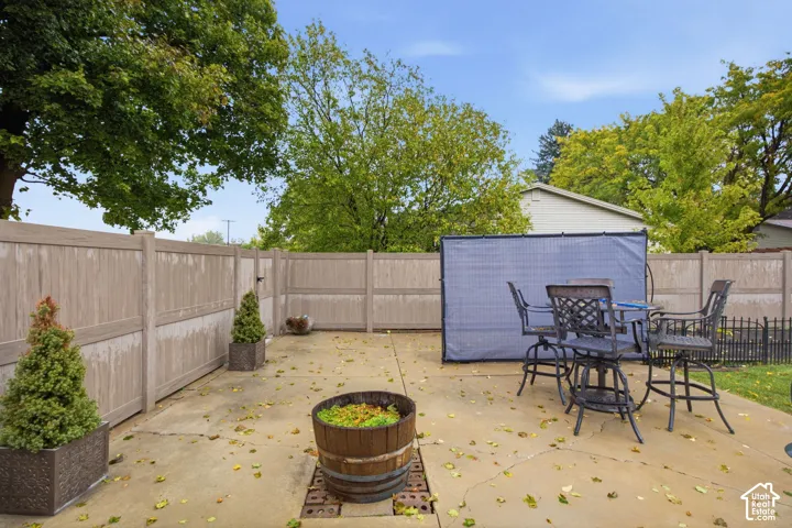 Concrete patio area enclosed by a privacy-height vinyl fence and mature trees