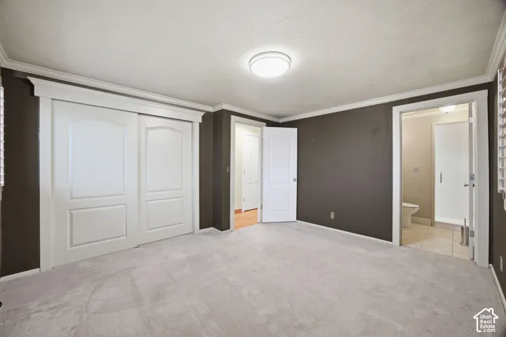 Primary Bedroom featuring crown molding, neutral carpeting, multi-panel closet doors, and recessed lighting
