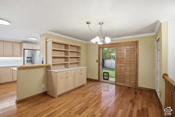 Dining area featuring wood-finish flooring, built-in cabinetry with stone-finish countertops, sliding glass door with wood-finish shutters, and multi-light hanging fixture