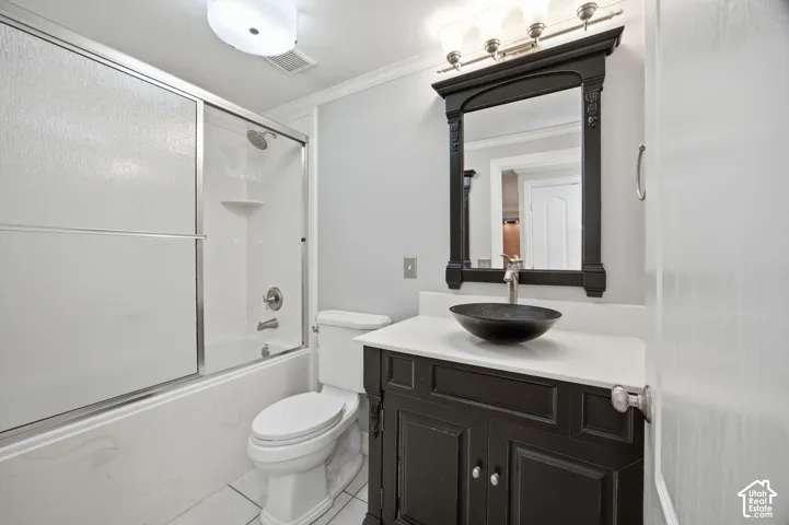 Bathroom featuring a dark-finish vanity with a light-toned countertop, a black vessel sink, a coordinating wall-mounted mirror, and a shower-tub combination with a glass sliding enclosure