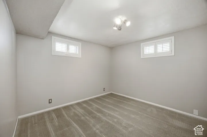 Bedroom #3 Neutral wall paint, plush carpeting, two windows with white shutter-style coverings, and three-bulb flush-mount ceiling light fixture