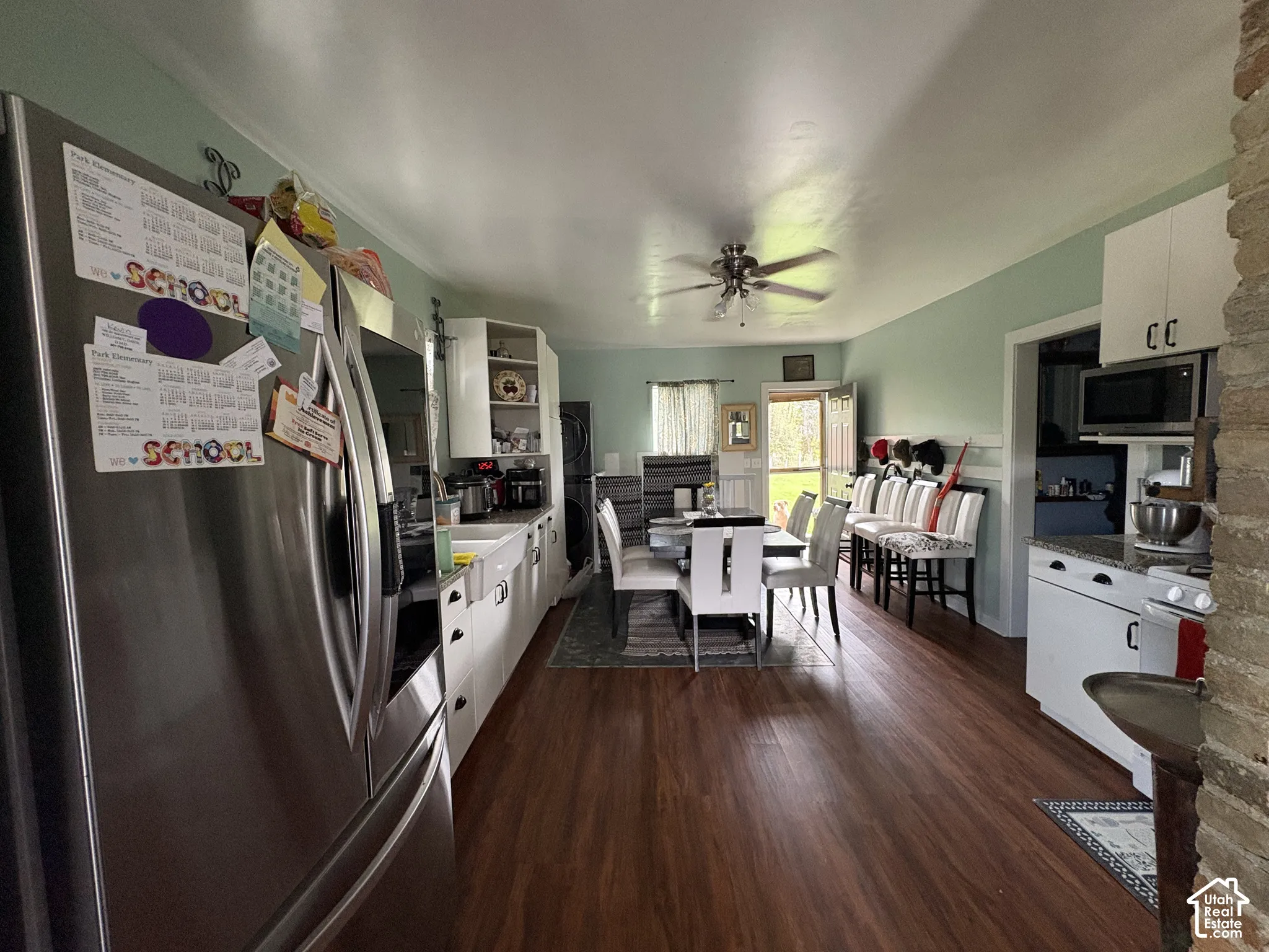 Kitchen featuring wood-finish flooring, white cabinetry, a farmhouse-style sink, stone-finish countertops, and a ceiling fan