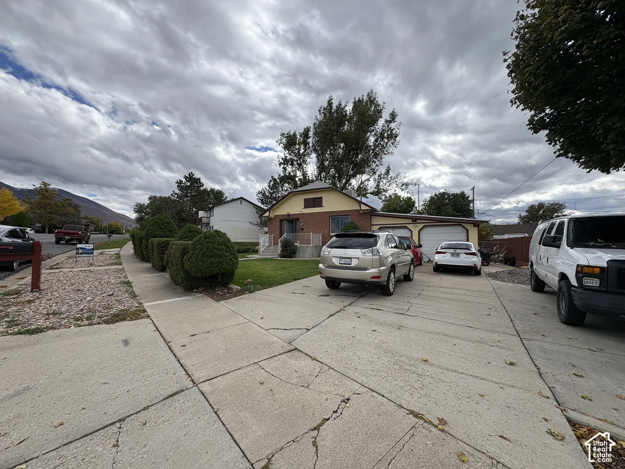 Single-story residence featuring brick masonry siding, an attached two-car garage, concrete driveway, and front landscaping with manicured shrubbery