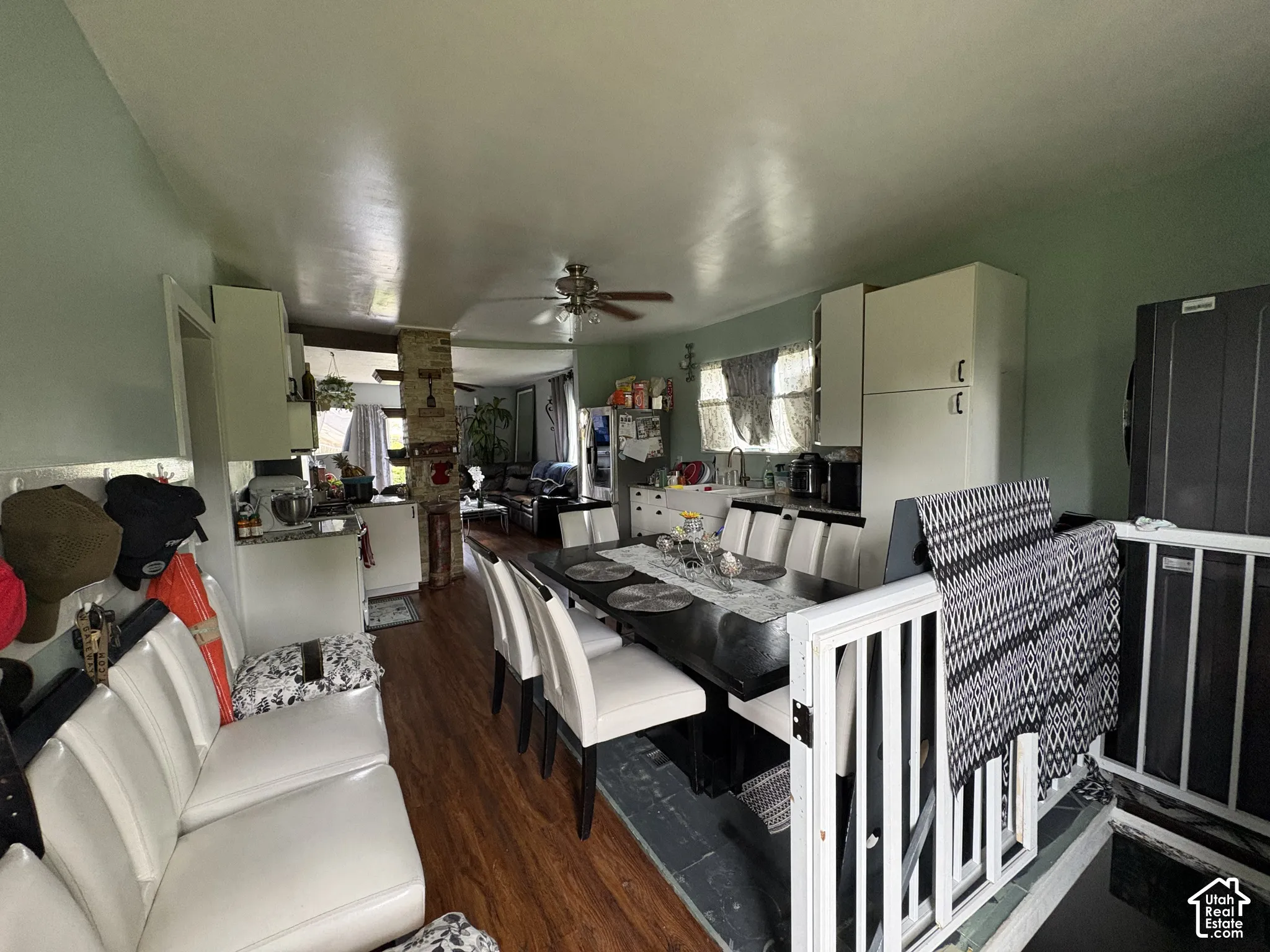Kitchen and dining area featuring wood-finish flooring, white cabinetry, a stone-accented pillar, and a ceiling fan