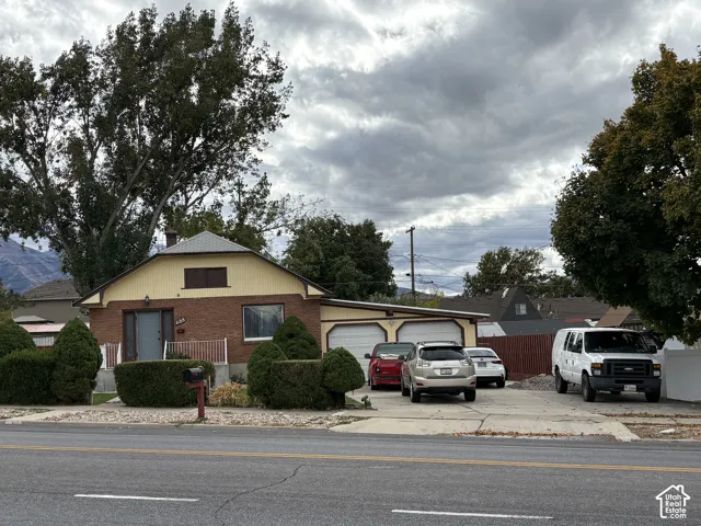 Single-story residence featuring a brick and panel exterior, a two-car attached garage, a concrete driveway, and mature landscaping