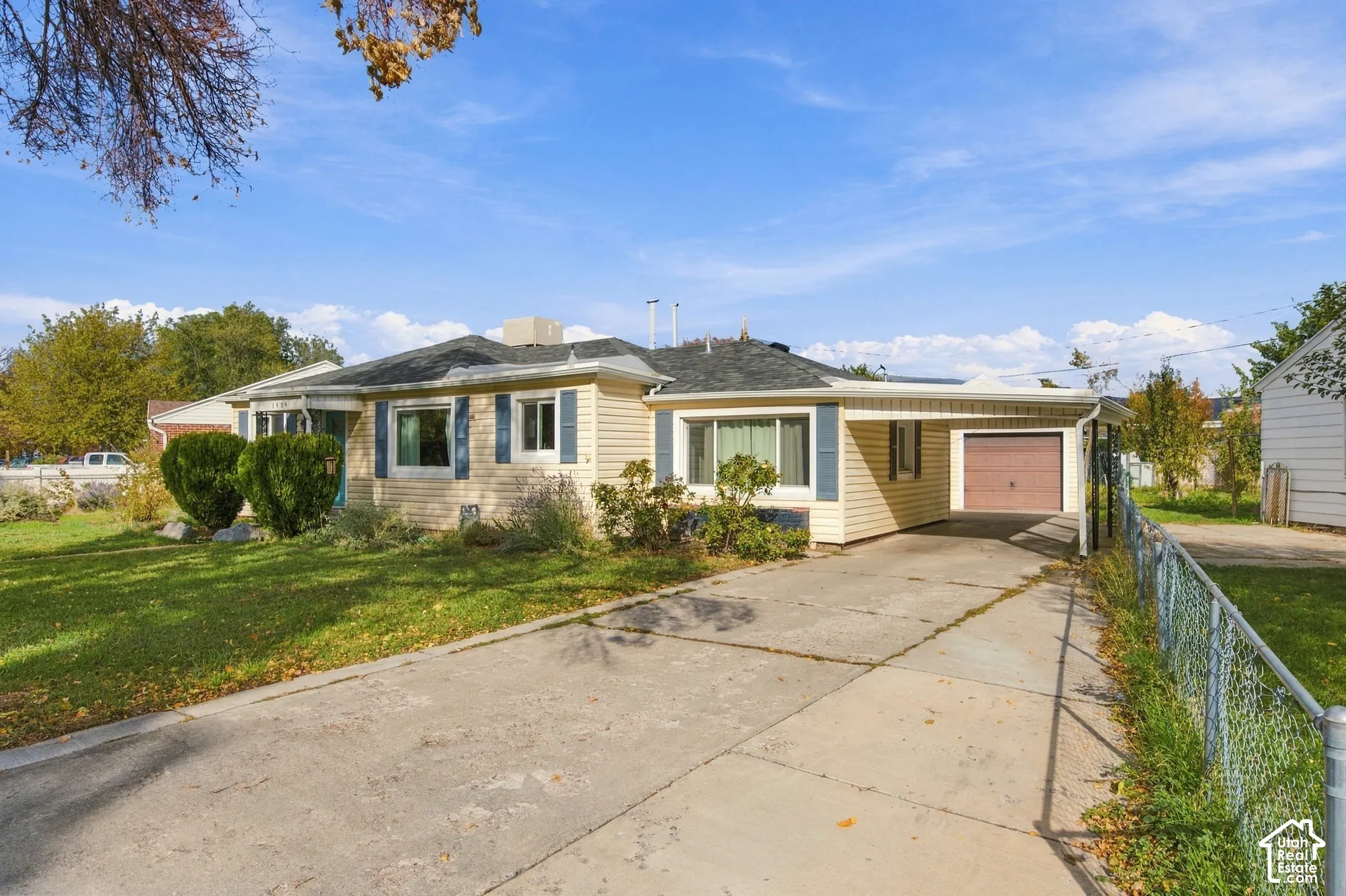 Single-story residence featuring siding, shutters, a concrete driveway, an attached carport, and a private garage