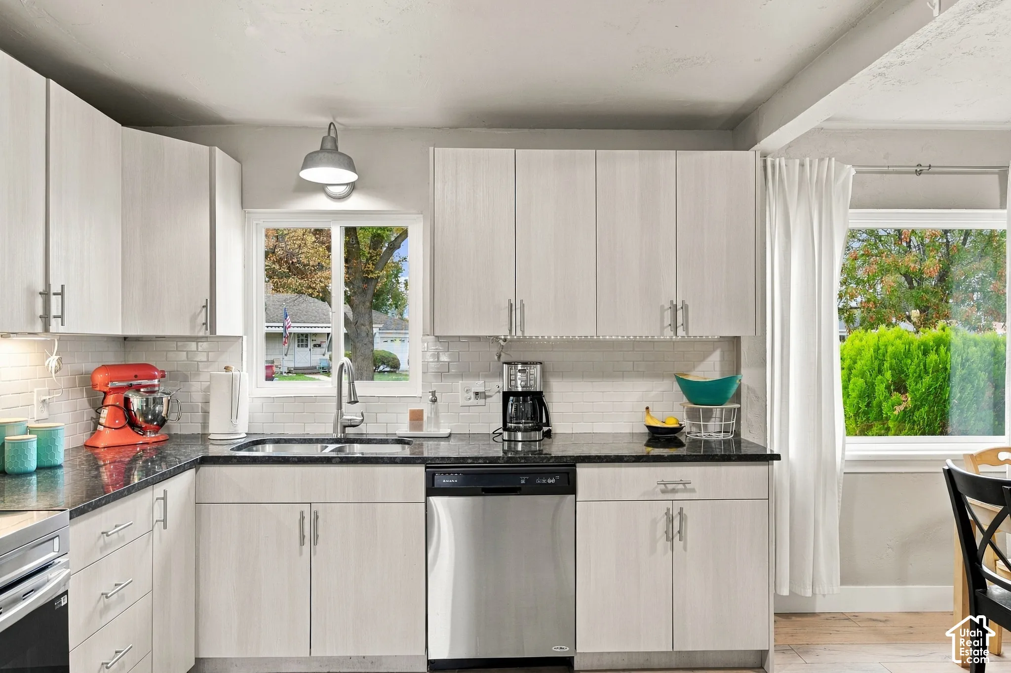Kitchen featuring light-finish cabinetry, white subway tile backsplash, stainless steel dishwasher